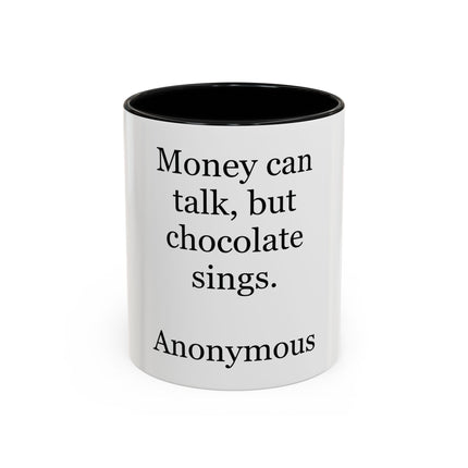 White ceramic accent mug with colored interior and handle, featuring the quote “Money can talk, but chocolate sings.”